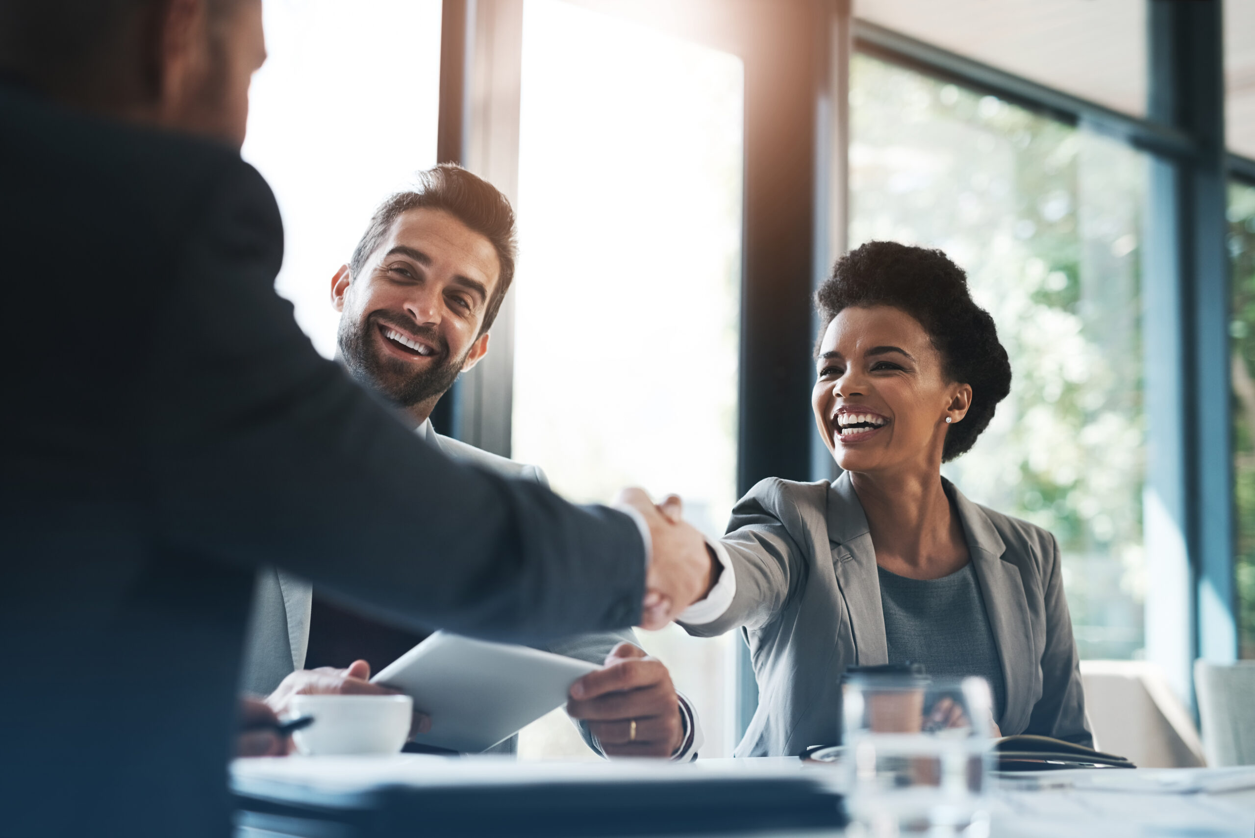 Three young employees working together in office and shaking hands